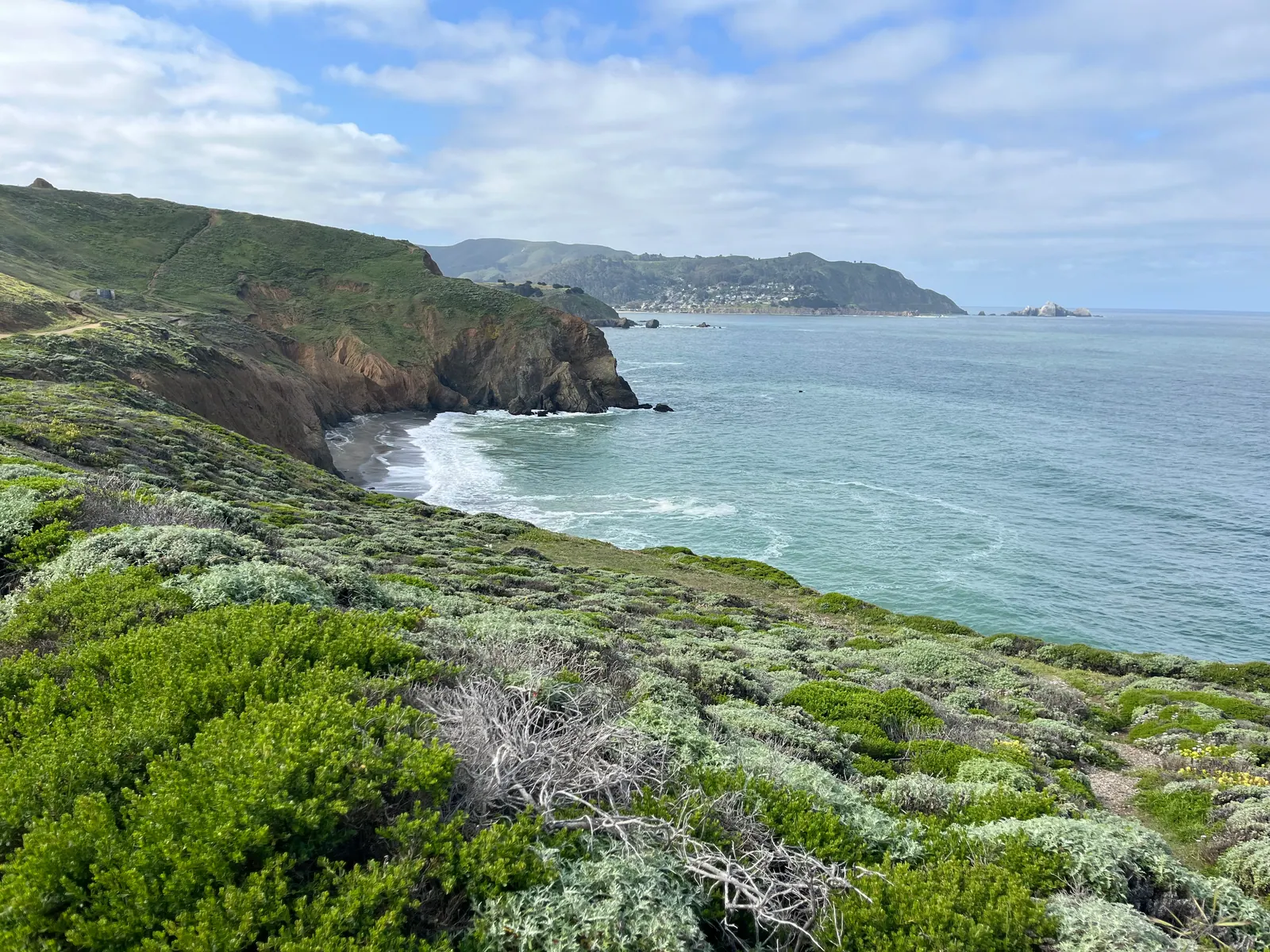 Coastal bluffs and a small cove at Mori Point in Pacifica, California, with hillside homes visible in the distance