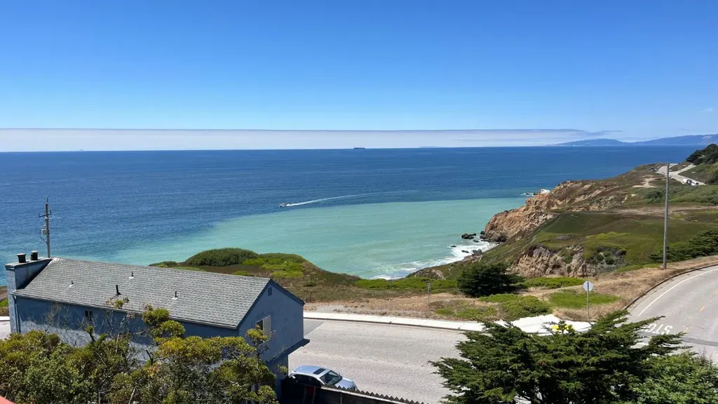 Ocean view from a coastal home in Pacifica California overlooking cliffs, shoreline, and the Pacific Ocean on a clear day