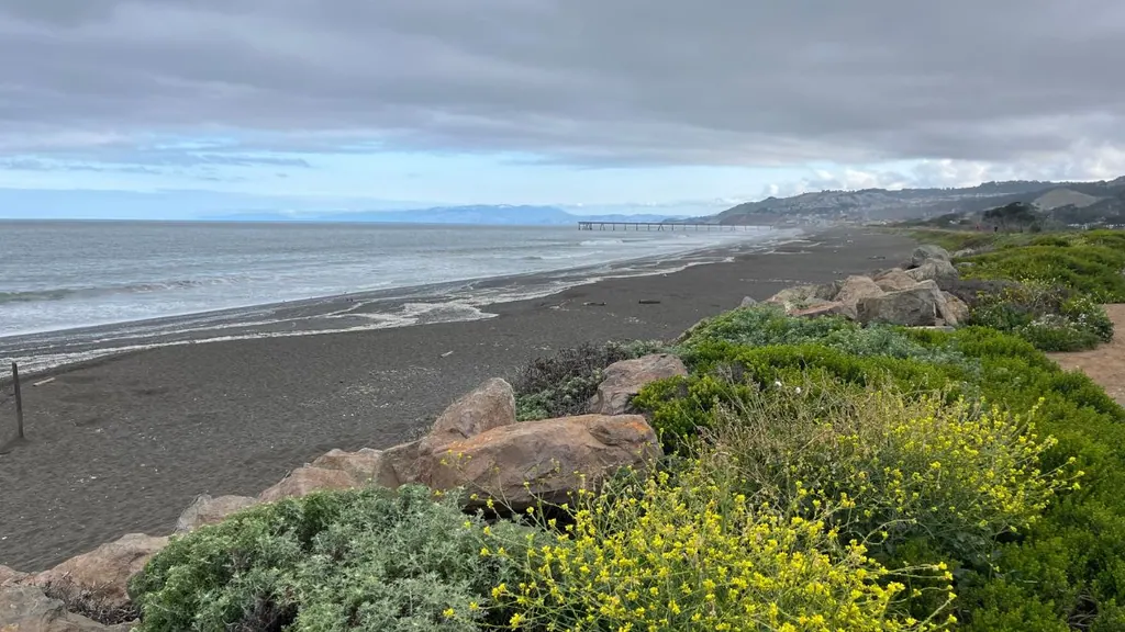 Sharp Park Beach in Pacifica, California, with ocean, coastline, rocks, and the Pacifica Pier in the distance