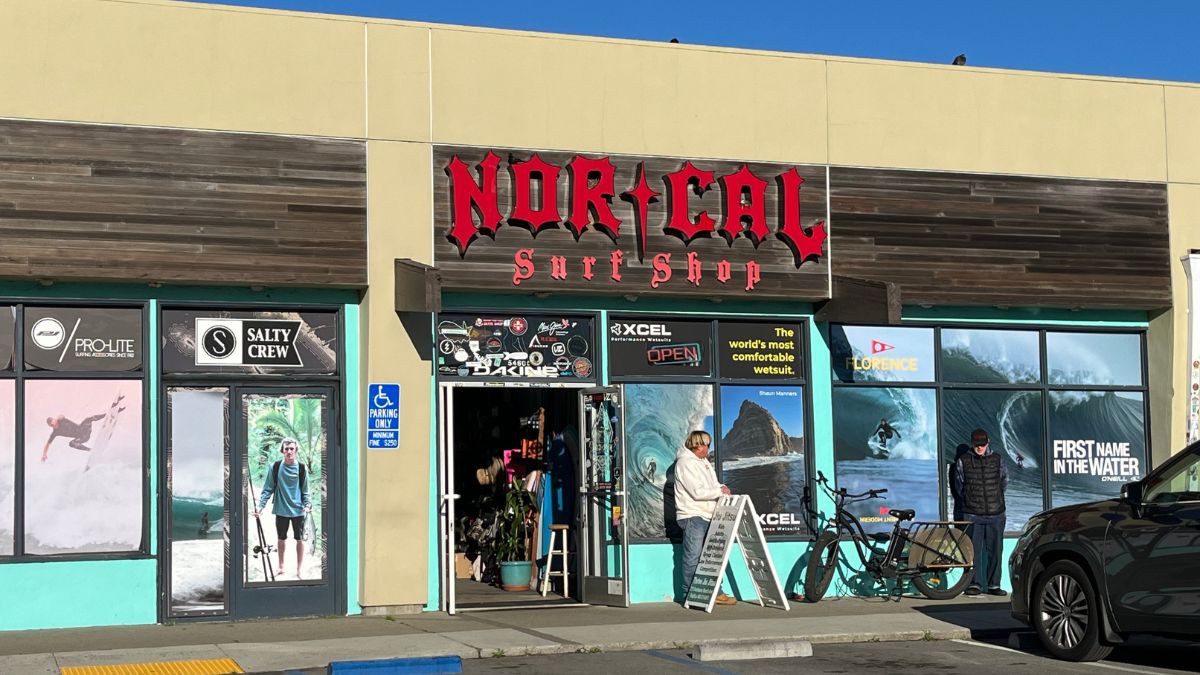 NorCal Surf Shop storefront in Pacifica, California, with red NorCal Surf Shop sign, surf brand window displays, and entrance facing the street.