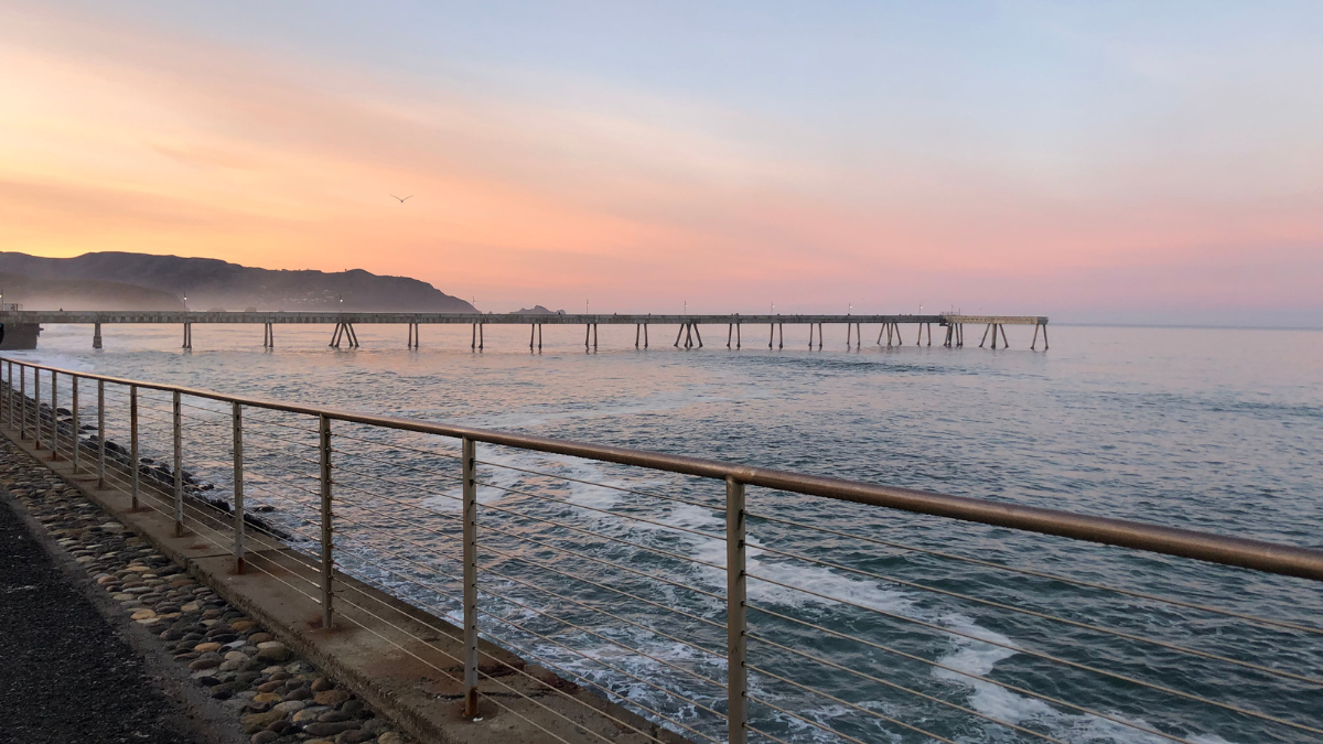 Here are a few Coastal Compass–aligned alt text options you can use, depending on tone and SEO intent: Clean + SEO-Friendly Sunset over Pacifica Pier in San Mateo County with soft orange sky reflecting on the ocean.